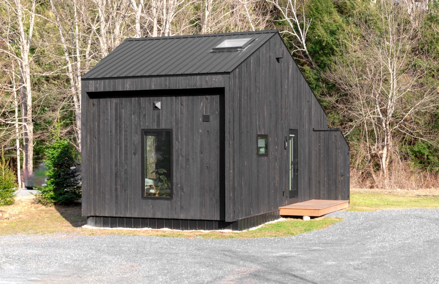 The Outrider — compact black-clad studio shed home among trees